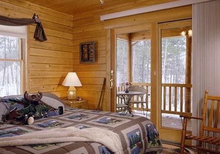 Log home bedroom with doors leading to deck