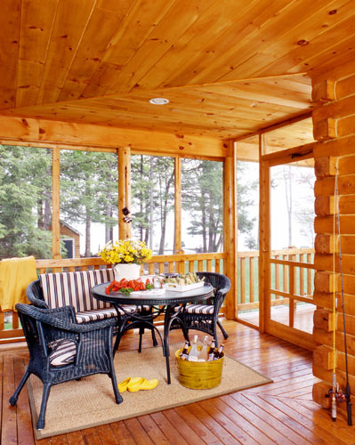 Screened in porch of log home with furniture