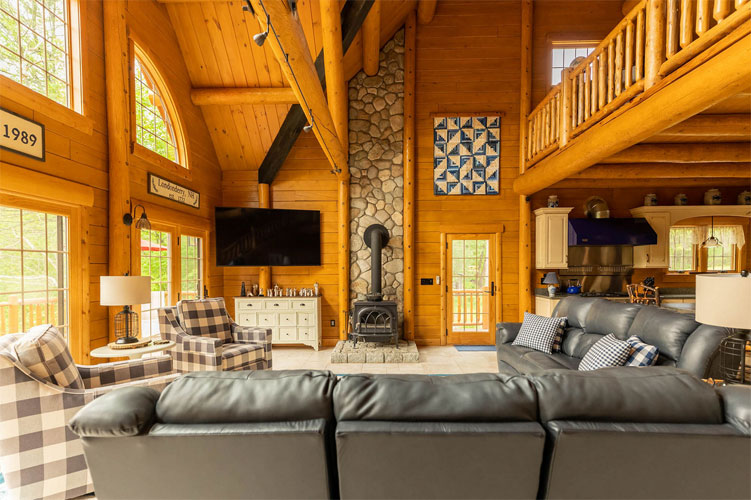 Luxury log home Great Room with large gable glass and stone fireplace