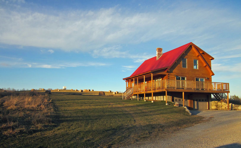 Log home in field with red roof