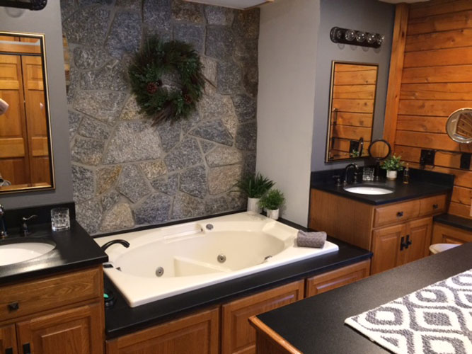 Log Bathroom with double sinks separated by large jet tub