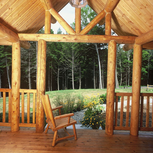 Log home porch with log truss looking out to the woods